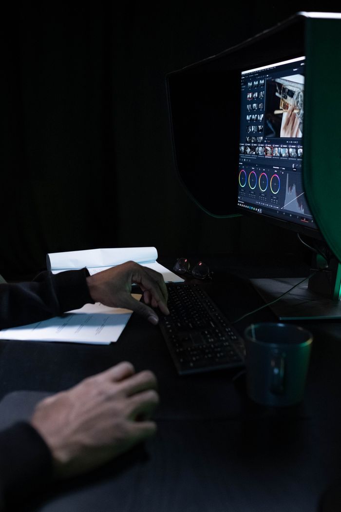 Close-up of a video editor working on color grading in a dimly lit room.